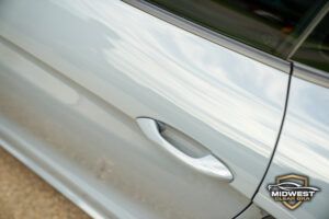Gray Porsche Cayman after professional paint protection film (PPF), ceramic coating, and window tint installation, shown at a front three quarter angle with clear bra film protecting the hood, bumper, and fenders.