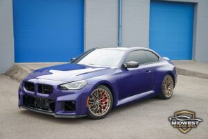 A purple BMW M2 CS with bronze M wheels and red brake calipers, after XPEL paint protection film, ceramic coating, and window tint installation at Midwest Clear Bra.