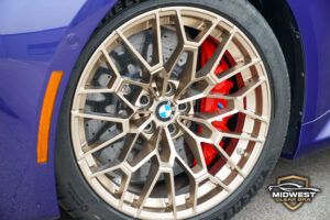 A purple BMW M2 CS with bronze M wheels and red brake calipers, after XPEL paint protection film, ceramic coating, and window tint installation at Midwest Clear Bra.