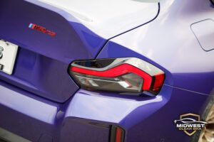 A purple BMW M2 CS with bronze M wheels and red brake calipers, after XPEL paint protection film, ceramic coating, and window tint installation at Midwest Clear Bra.